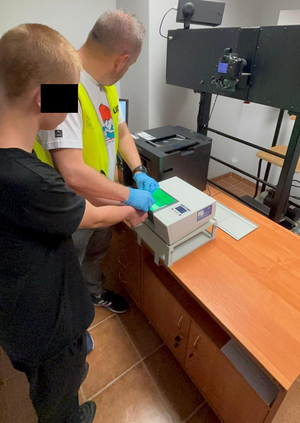 Policjant pobiera od zatrzymanego odciski palców.
