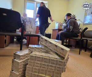 w komisariacie rozłożone paczki z papierosami. Mężczyzna w kajdankach.