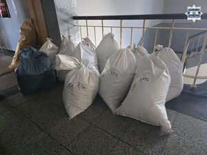 w komisariacie rozłożone paczki z papierosami. Mężczyzna w kajdankach.