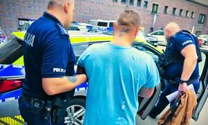 policjanci prowadzą zatrzymanego.