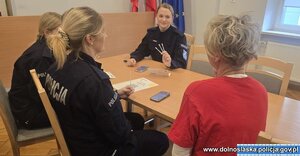 Trzy policjantki siedzą przy stole z kobietą.