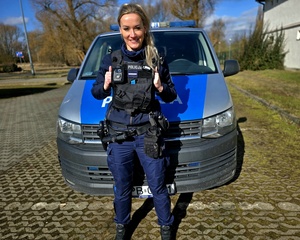 policjantka stoi przed radiowozem.