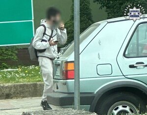 Mężczyzna z plecakiem przy samochodzie osobowym.