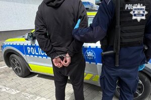 Policjant prowadzi osobę zatrzymaną.