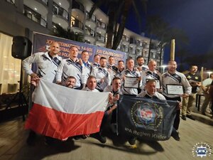 Drużyna KWP w Kielcach pozuje do zdjęcia grupowego trzymając polską flagę.