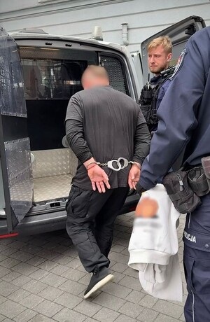 Zatrzymany prowadzony przez policjanta.
