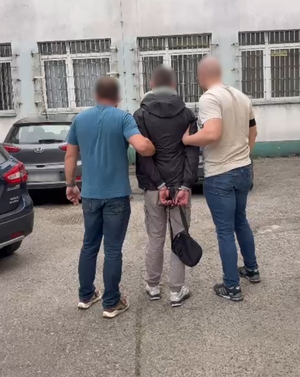Dwaj policjanci prowadzą zatrzymanego mężczyznę.
