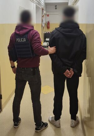 Policjant prowadzi zatrzymanego 16-latka.