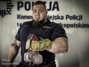Policjant trzyma w ręku zdobyte medale.