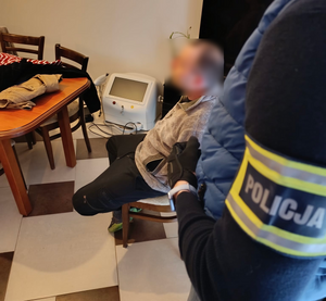 zatrzymany siedzi na krześle, obok leży odzyskany sprzęt.