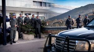 Kompilacja dwóch zdjęć. Po lewej stronie widoczny jest budynek, a przed nim policjanci, którzy kiedyś pełnili misje poza granicami państwa, a po prawej auto i trzej stojący policjanci w niebieskich beretach, którzy patrzą na góry.