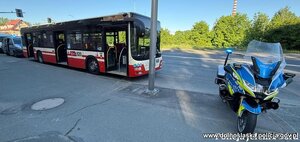 Autobus, a przed nim policyjny motocykl.