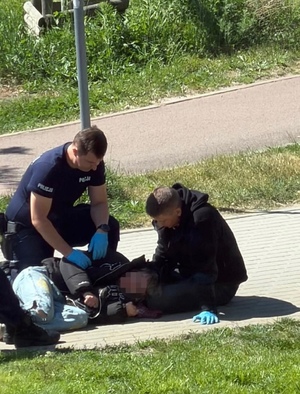 Policjanci udzielają pomocy mężczyźnie, który zasłabł.