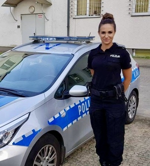 Policjantka przy radiowozie pozuje do zdjęcia.