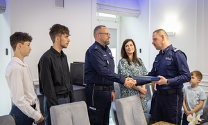 Uczestnicy spotkania w KGP. Policjant z rodziną oraz policjanci z komendantem głównym Policji na czele.