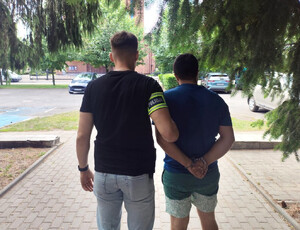 Policjant prowadzi zatrzymanego.