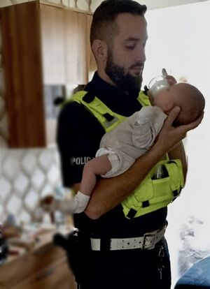 Policjant trzyma dziecko na rękach.