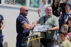 Mężczyzna ściska dłoń policjantowi, wokół widać inne osoby.