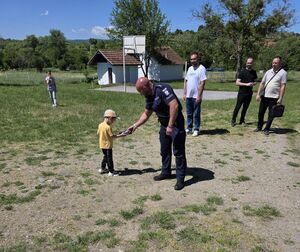 Policjant wręcza dziecku upominek.