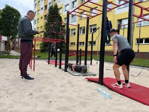 Policjanci w trakcie wykonywania sportowego wyzwania - ćwiczenia na drążku.