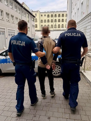 Dwaj policjanci prowadzą zatrzymanego.