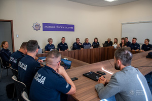 Policjanci siedzący w sali przy stołach na obradach.