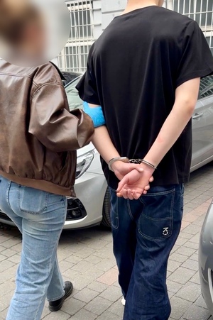 policjantka prowadzi zatrzymanego.