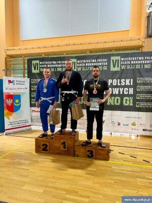 Podkomisarz Maciej Iwoła z Centralnego Laboratorium Kryminalistycznego Policji i dwaj inni zawodnicy na podium.