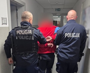 dwóch policjantów stoi z zatrzymanym.
