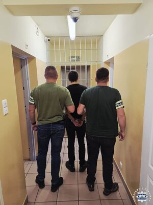 dwóch policjantów stoi z zatrzymanym.