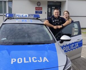 Dwoje policjantów stoi przy otwartych drzwiach radiowozu.
