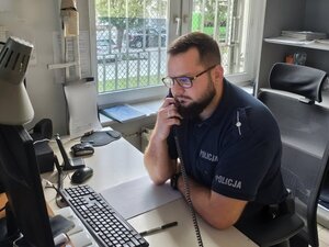 policjant siedzi przy biurku.