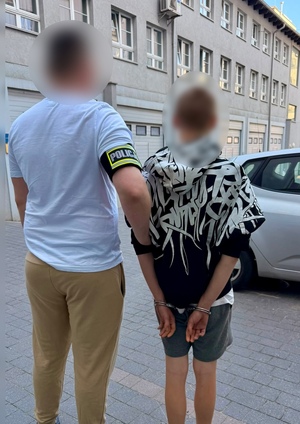 policjant prowadzi zatrzymanego.
