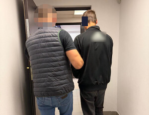 policjant prowadzi zatrzymanego.