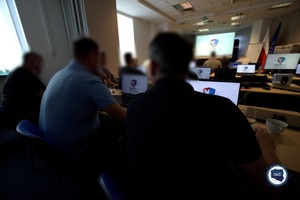 Grupa funkcjonariuszy siedzi przy komputerach.