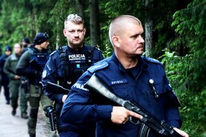 policjanci idą przez las z bronią.