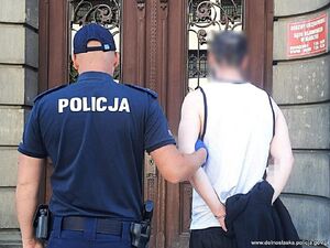 Policjant wprowadza zatrzymanego do sądu.