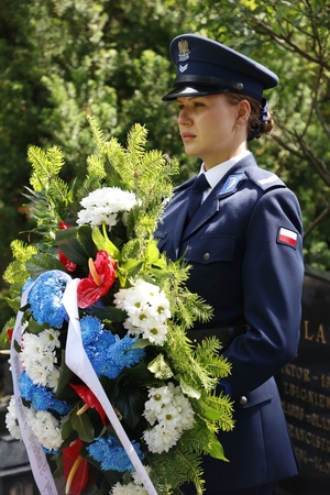 Policjantka niesie wieniec.