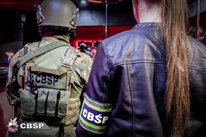 Policjant CBŚP i nieumundurowana policjantka z opaska CBŚP na ręku - widok z tyłu.