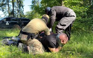 Dwaj mężczyźni zawiązują taśmę na oczach i rękach innych mężczyzn - policjanci podczas specjalistycznego szkolenia.