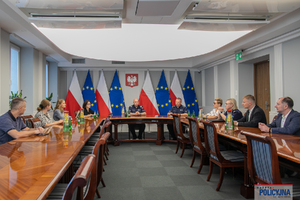 Zdjęcie zbiorowe uczestników spotkania, którzy siedzą na sali za stołami.