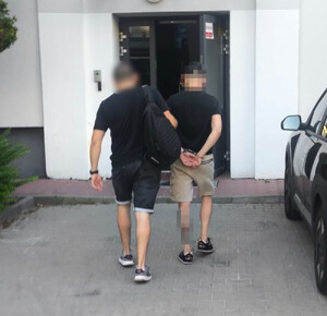 Policjant prowadzi zatrzymanego.