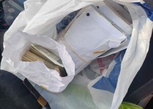 Zabezpieczone przez policjantów pieniądze w kopertach znajdujących się w foliowym worku.
