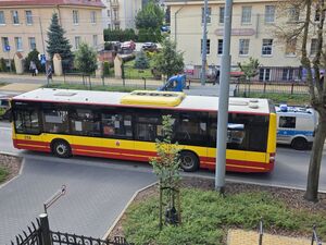 Stojący na jezdni autobus, obok widać policyjny radiowóz.