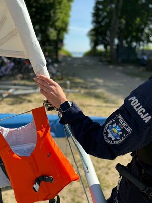 Policjantka trzyma masz przy którym zawieszona jest kamizelka.