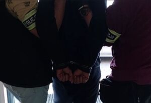 Dwaj policjanci prowadzą zatrzymanego.