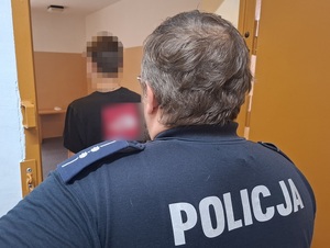 Odwróceni tyłem funkcjonariusz i zatrzymany.