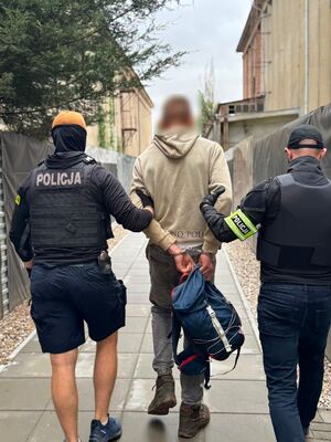 Dwaj policjanci prowadzą zatrzymanego.