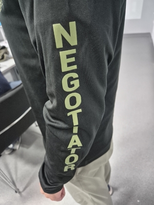 Napis Negotiator na rękawie bluzy mężczyzny.