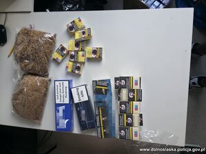 Zabezpieczone paczki papierosów i woreczki z tytoniem leżące na stole.